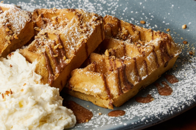 Belgian waffles with powdered sugar and whipped cream on a blue plate